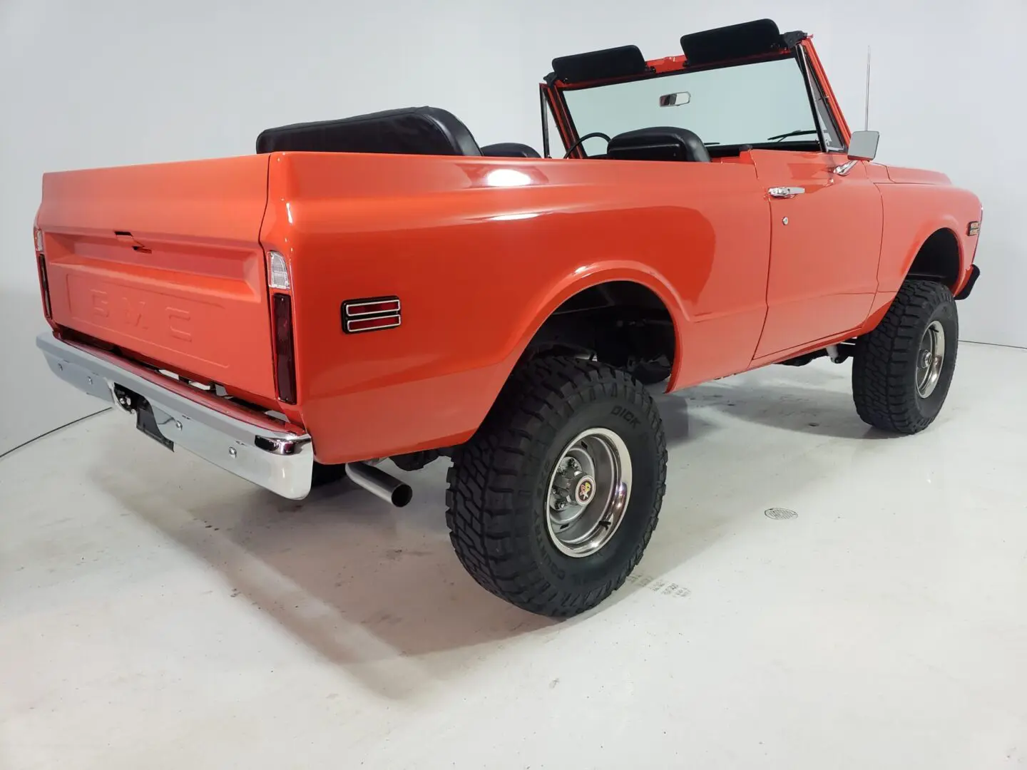 A red truck with large tires is parked in a room.