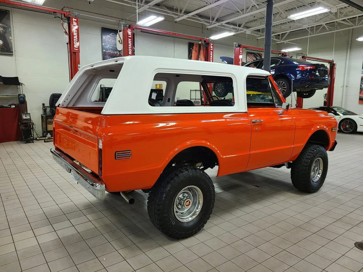 A red and white truck is parked in a garage.