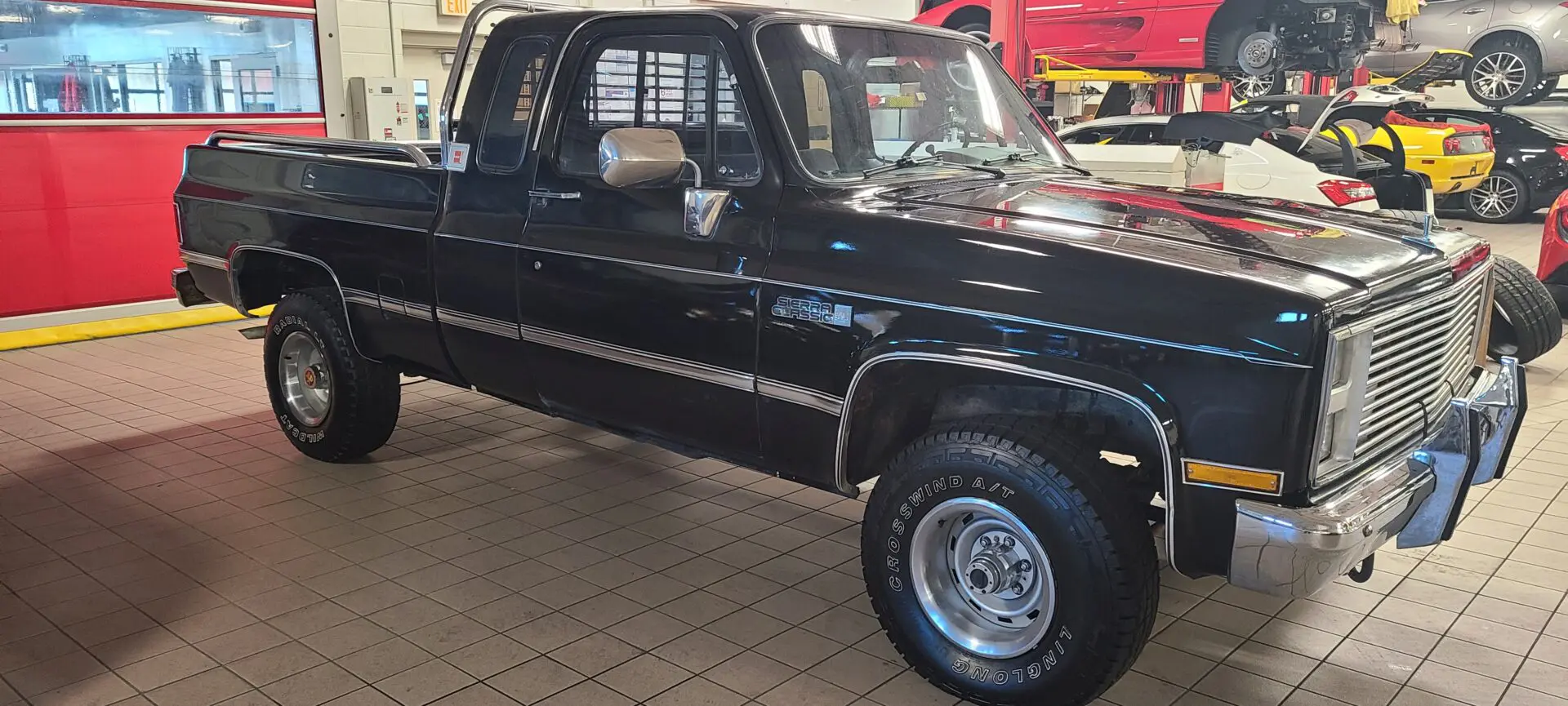 A black truck parked in a showroom with other vehicles.