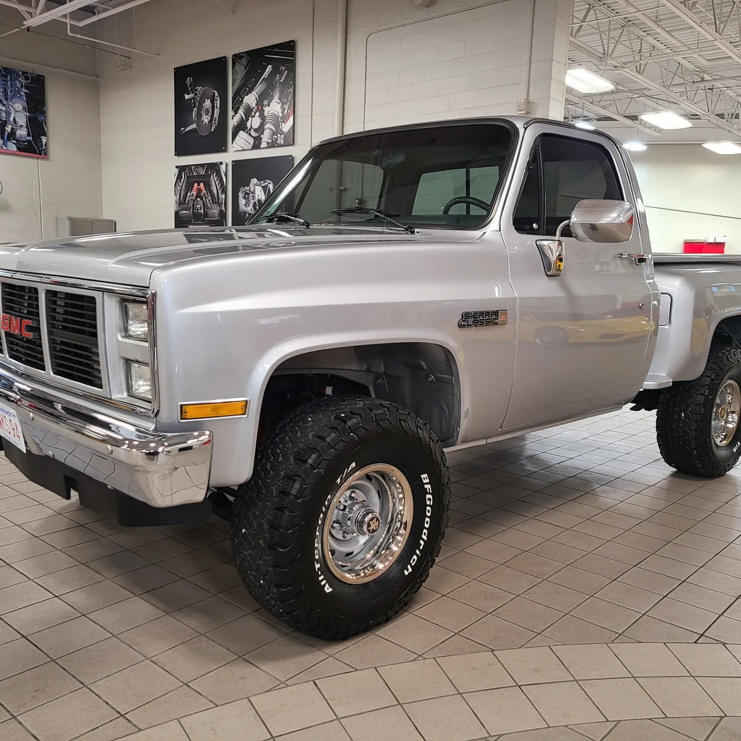 A silver truck is parked in a showroom.